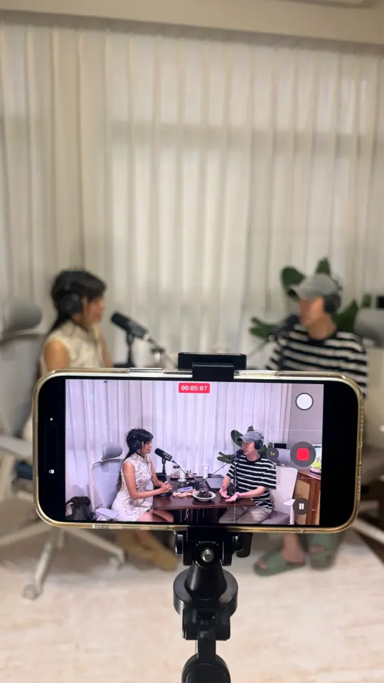 手機架在腳架上，錄下兩個人坐在桌邊對談